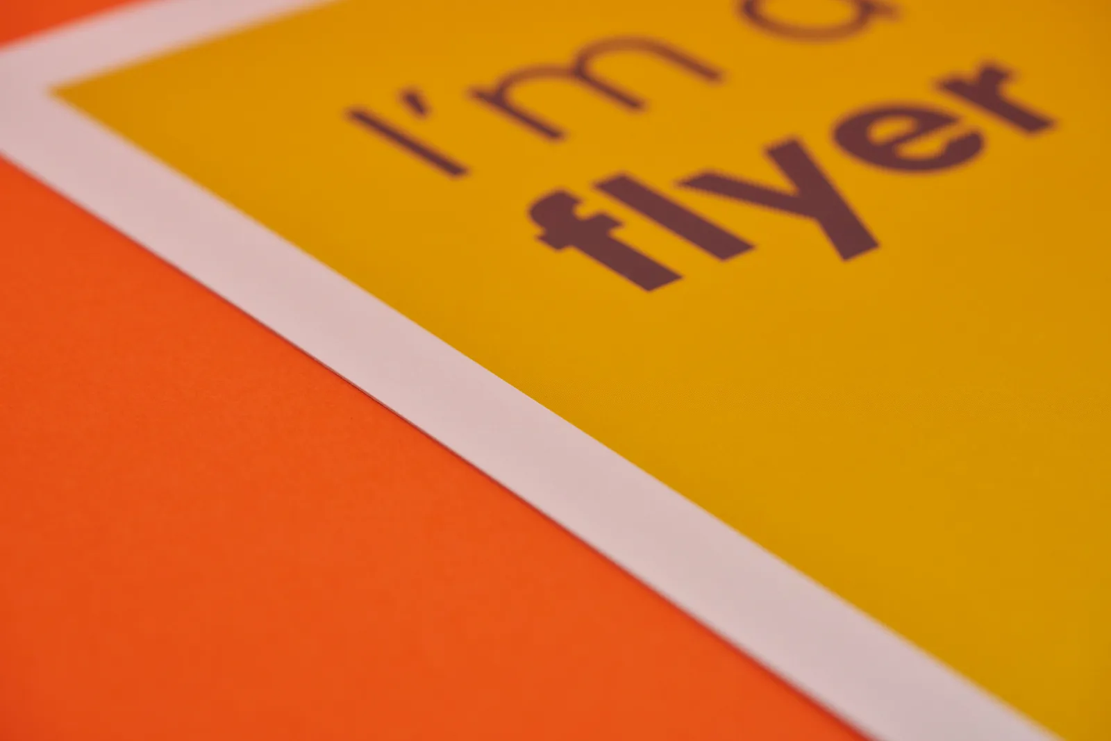 close up of a large yellow printed flyer with the text 'i'm a flyer' on a bright orange background