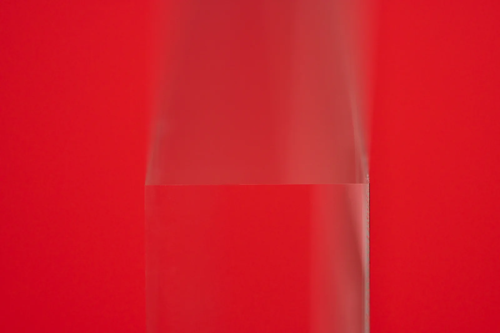 close up of a clear acrylic photo block from th eside showing the detail of the acrylic material on a bright red background
