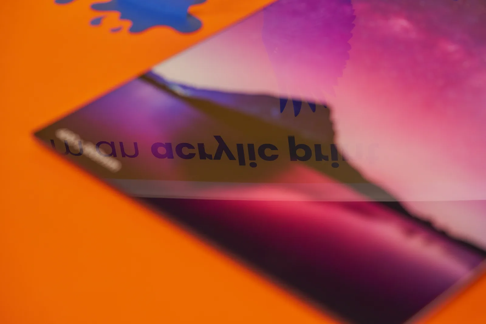 close up of a shiny purple acrylic print with high gloss reflection on a bright orange background