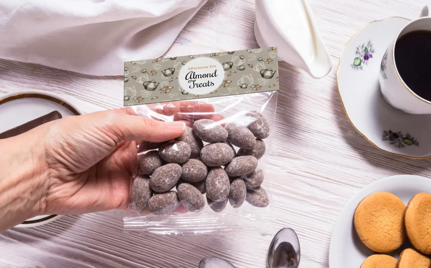 A person holds a bag of chocolate-covered nuts, packaged with an elegant bag topper card