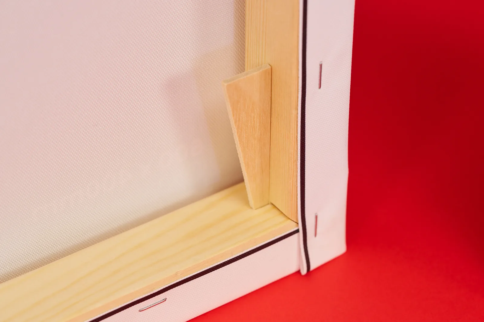 detail of the back of a canvas print showing wooden frame with stretched canvas stapled to frame and canvas stretcher peg