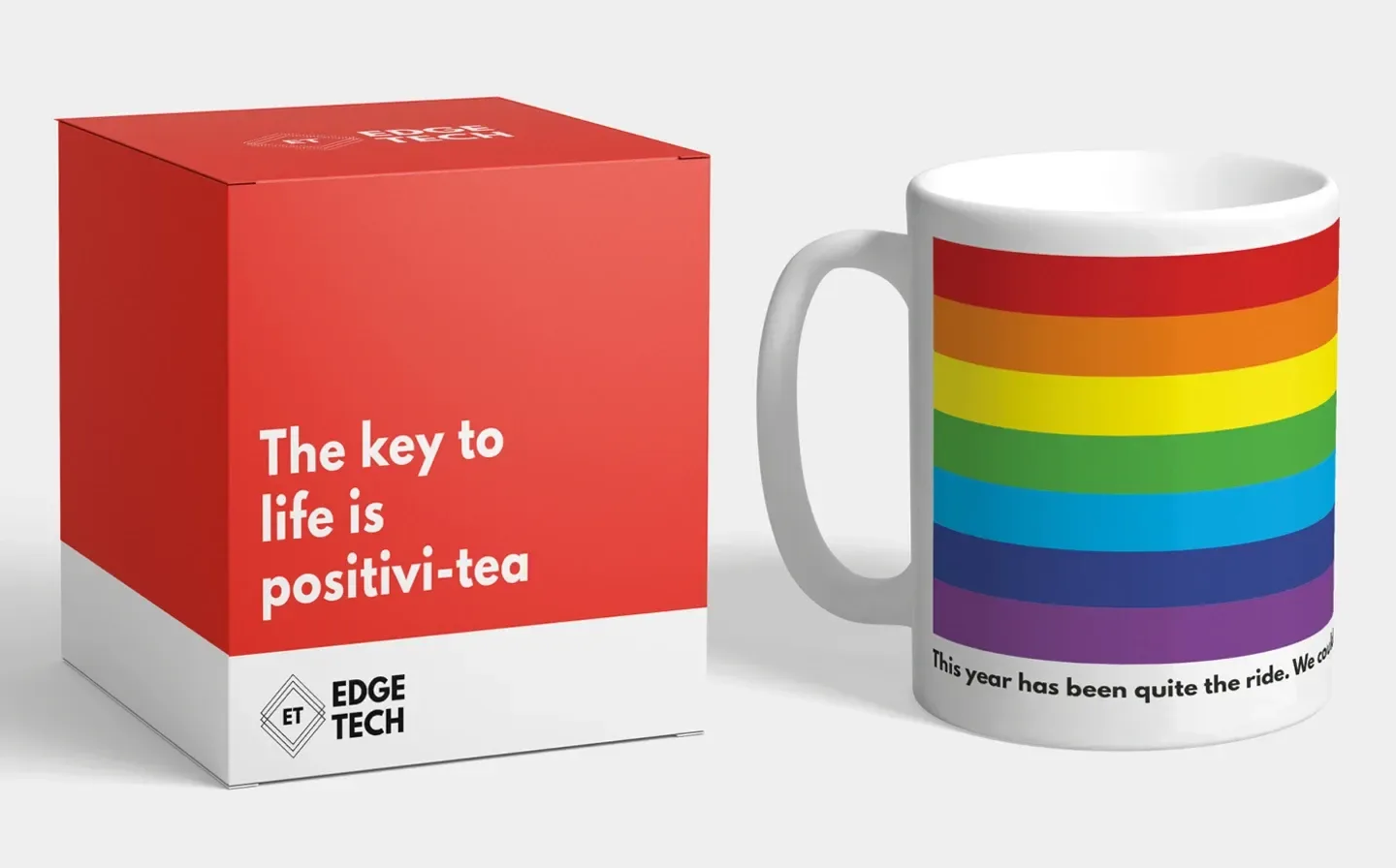 A red mug box alongside a rainbow mug with the phrase "The key to life is positivi-tea" displayed prominently