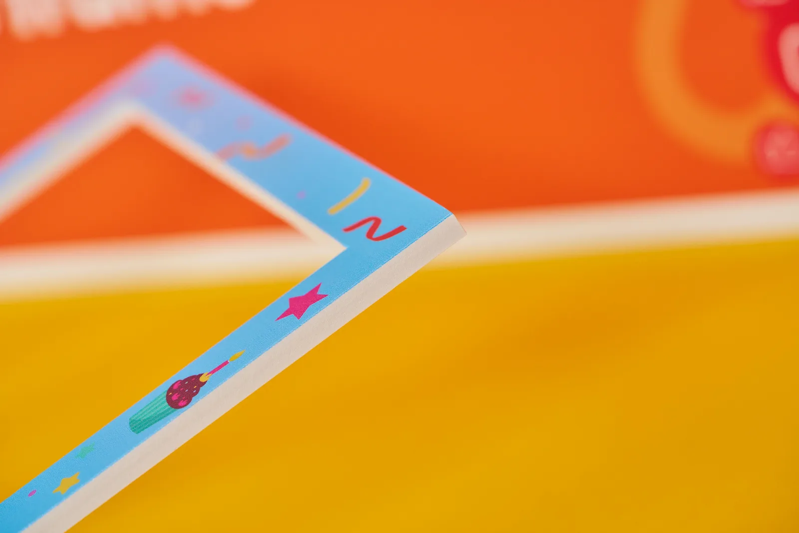 close up of a blue customised selfie frame showing detail of foamex on a bright yellow background with orange selfie frame in background
