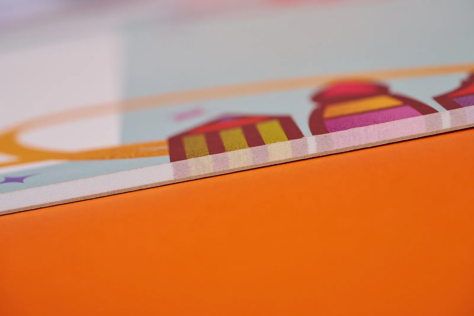 close up side of a printed desk pad showing thickness and number of pages on a bright orange background