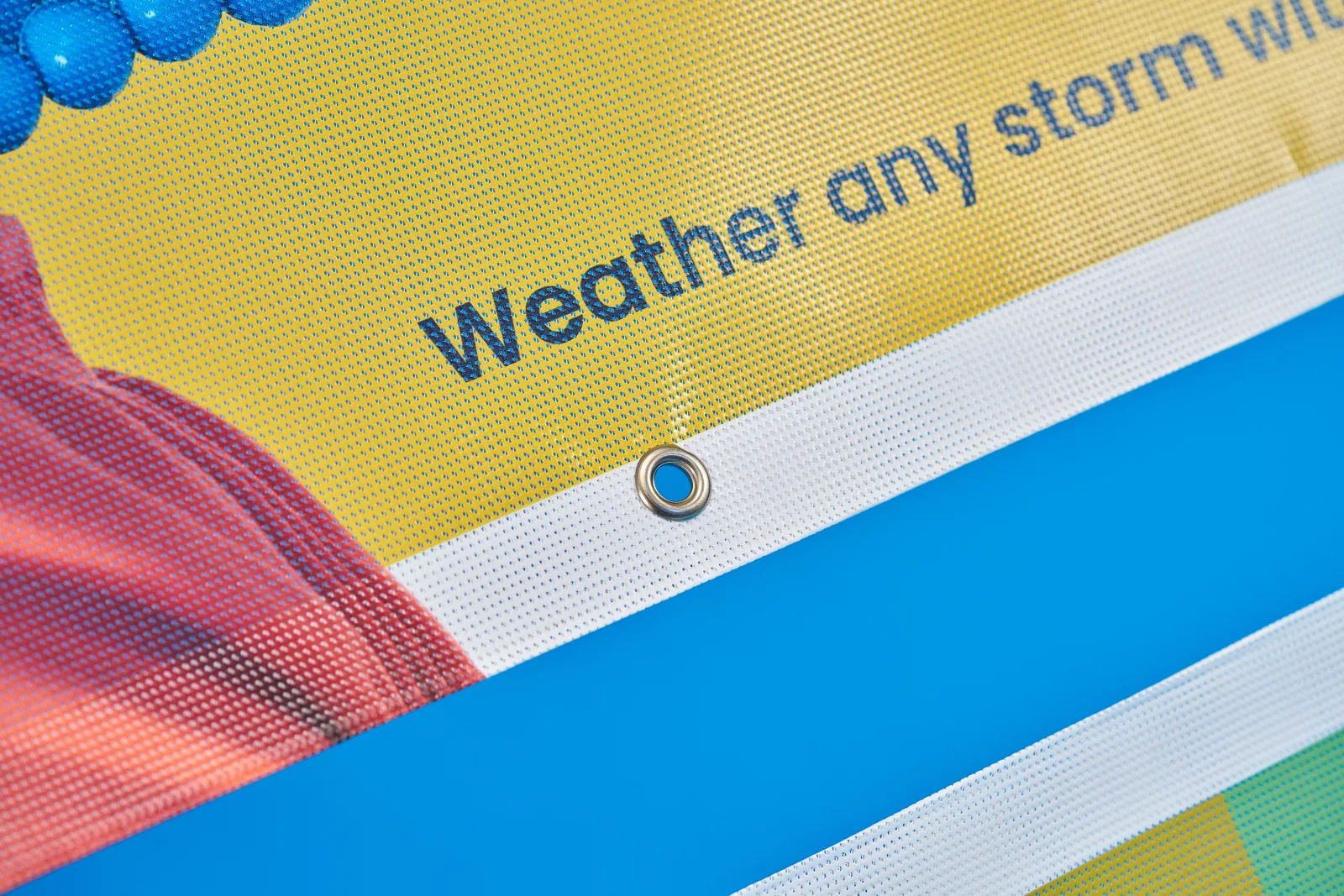printed outdoor mesh fence banner with eyelet and text 'weather any storm' on a bright blue background