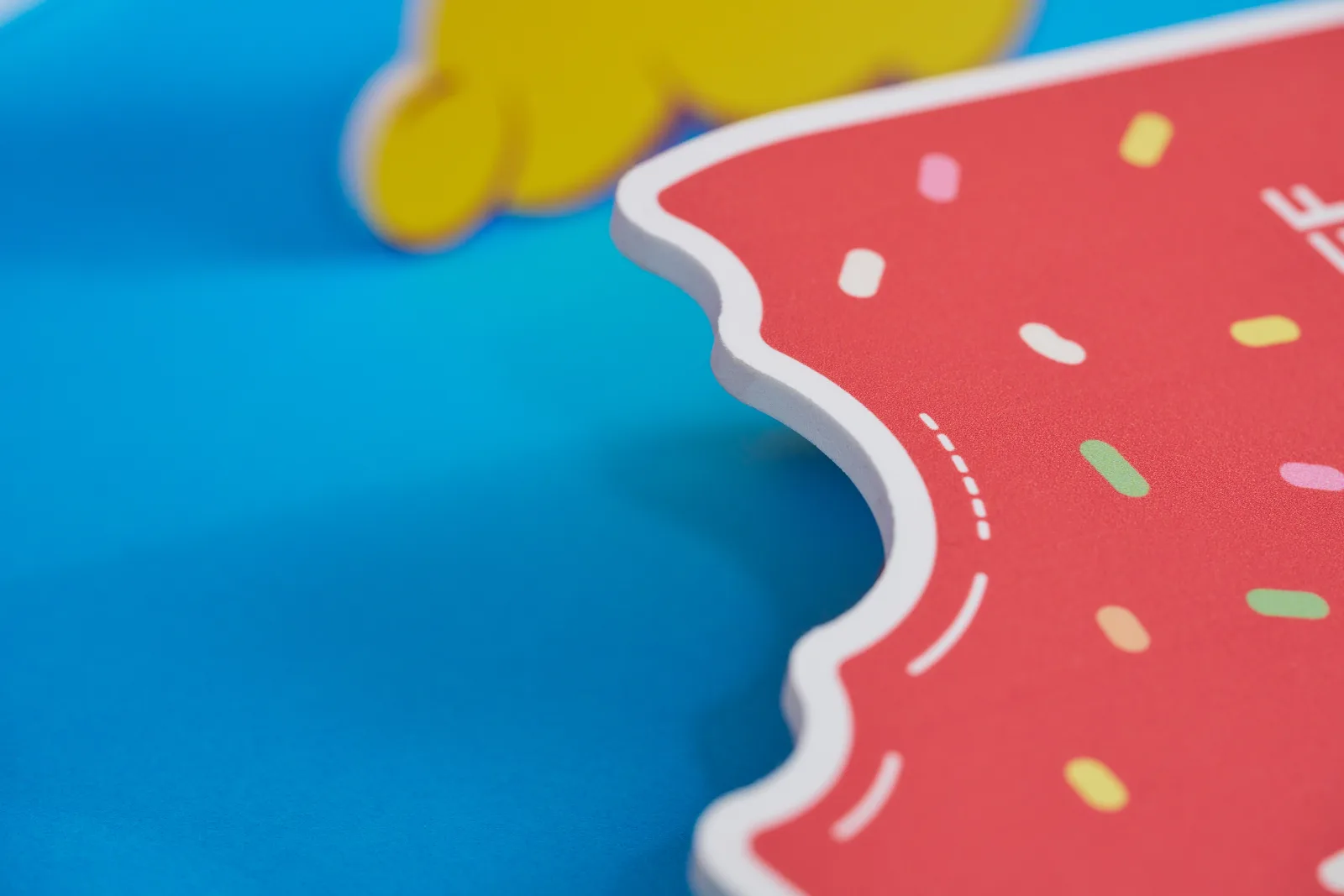 Close up of a red printed foamex sign showing detail of material and cutout teeth marks on a bright blue background