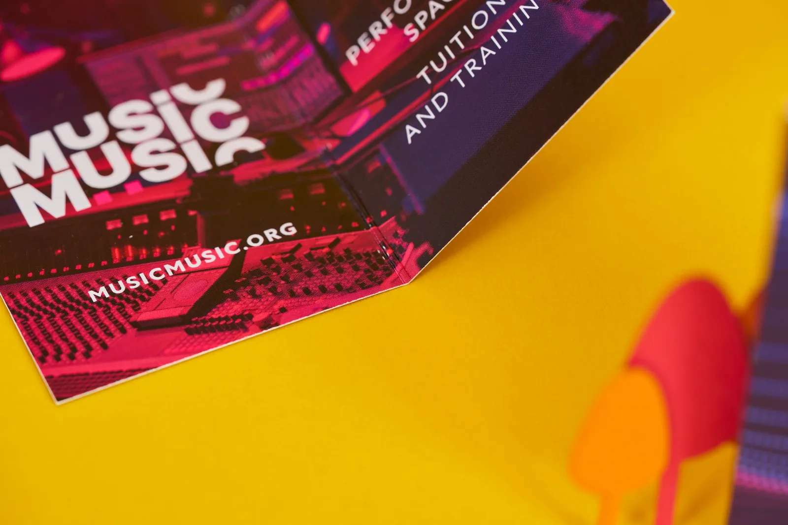 close up of a purple and pink printed folded business card with the text 'music' on a bright yellow background