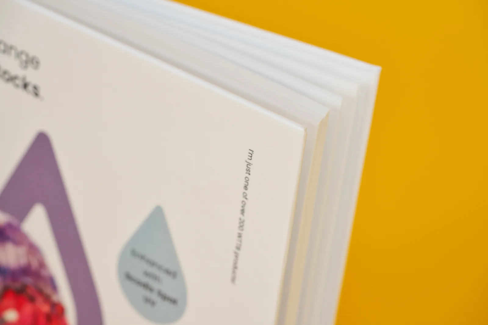 close up detail showing front and inner pages of a printed hardback books on a bright yellow background