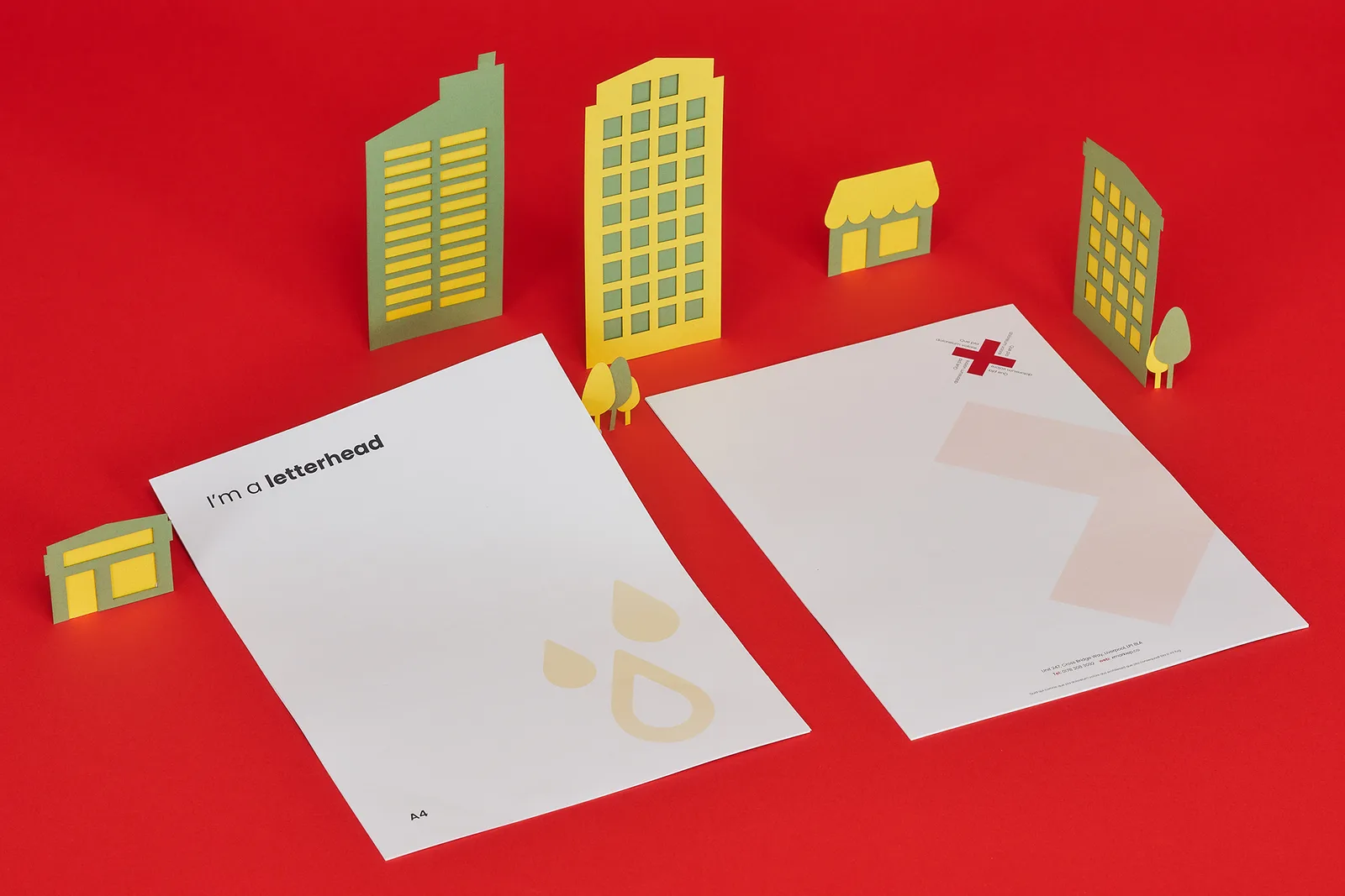 2 a4 printed letterheads one saying 'i'm a printed letterhead' on a bright red background with yellow and green paper buildings and trees