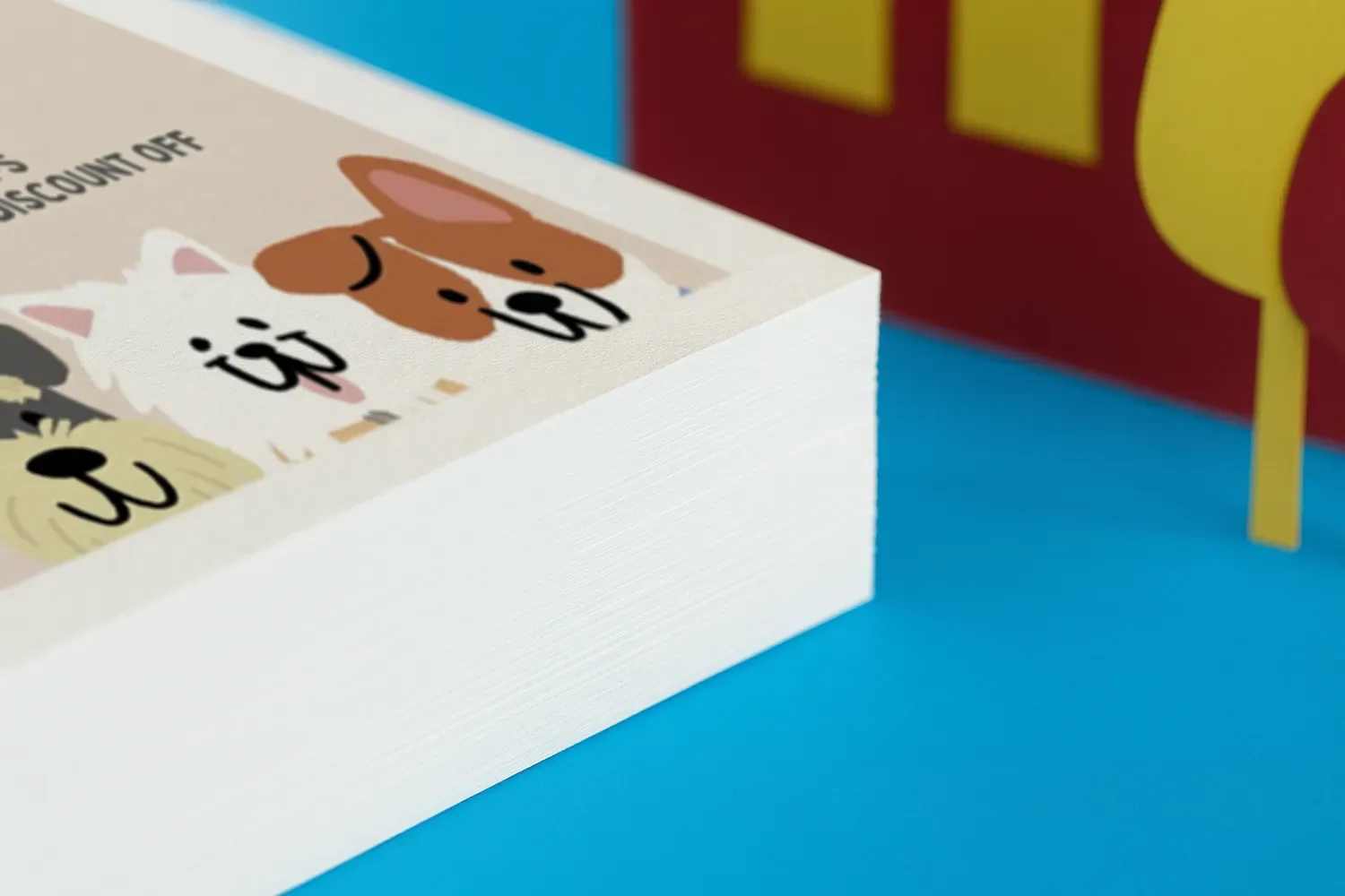 A stack of printed loyalty cards with cartoon dog faces on a blue surface.