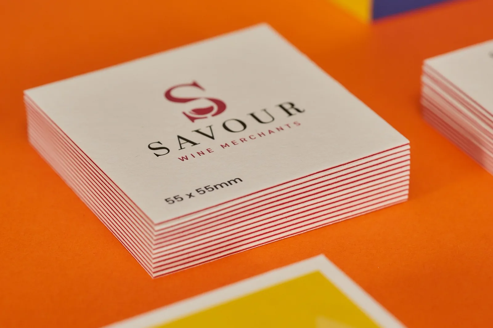 pile of white luxe business cards with purple centre and the copy 'savour' on a bright orange background