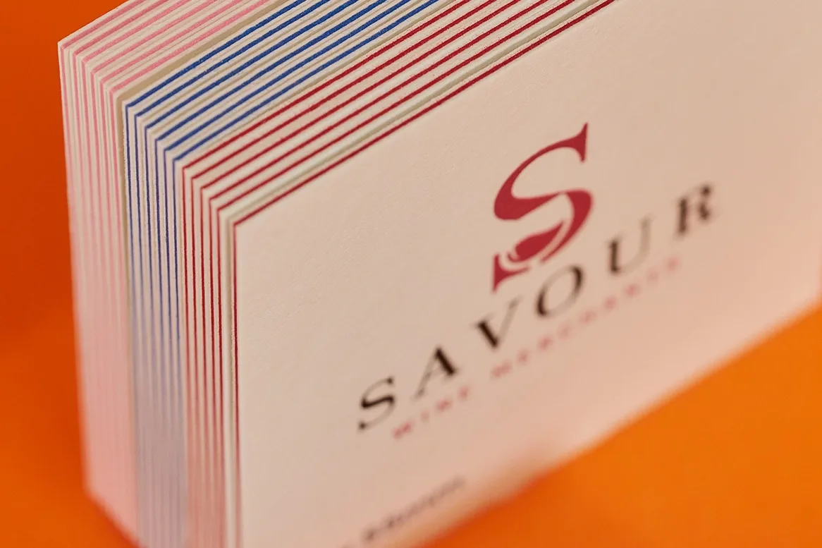 close up of luxe business cards showing detail of the centre colours red, blue and pink with the copy 'savour' on a bright orange background