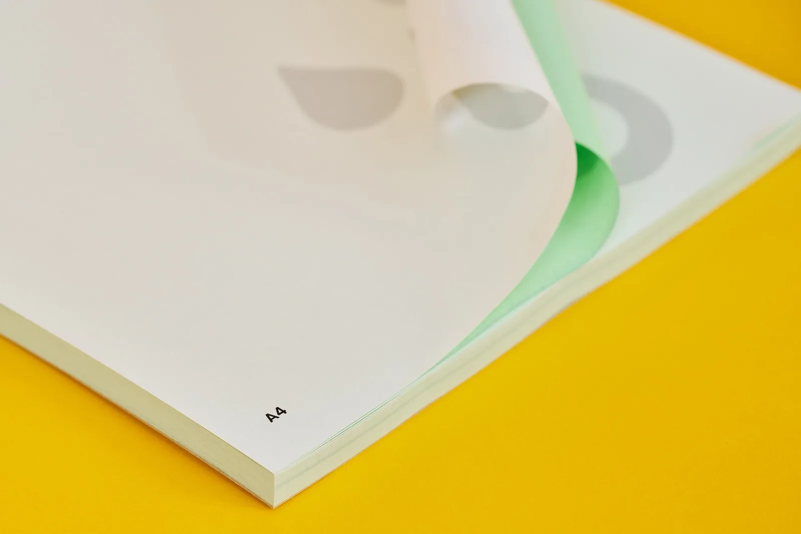 A4 ncr pad with white top sheet and green duplicate sheet on bright yellow background