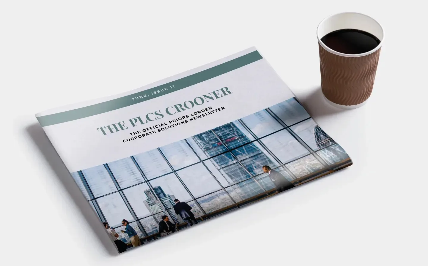 A newspaper featuring the title 'THE PLCS CROONER' on the cover on a white table with a coffee cup next to it