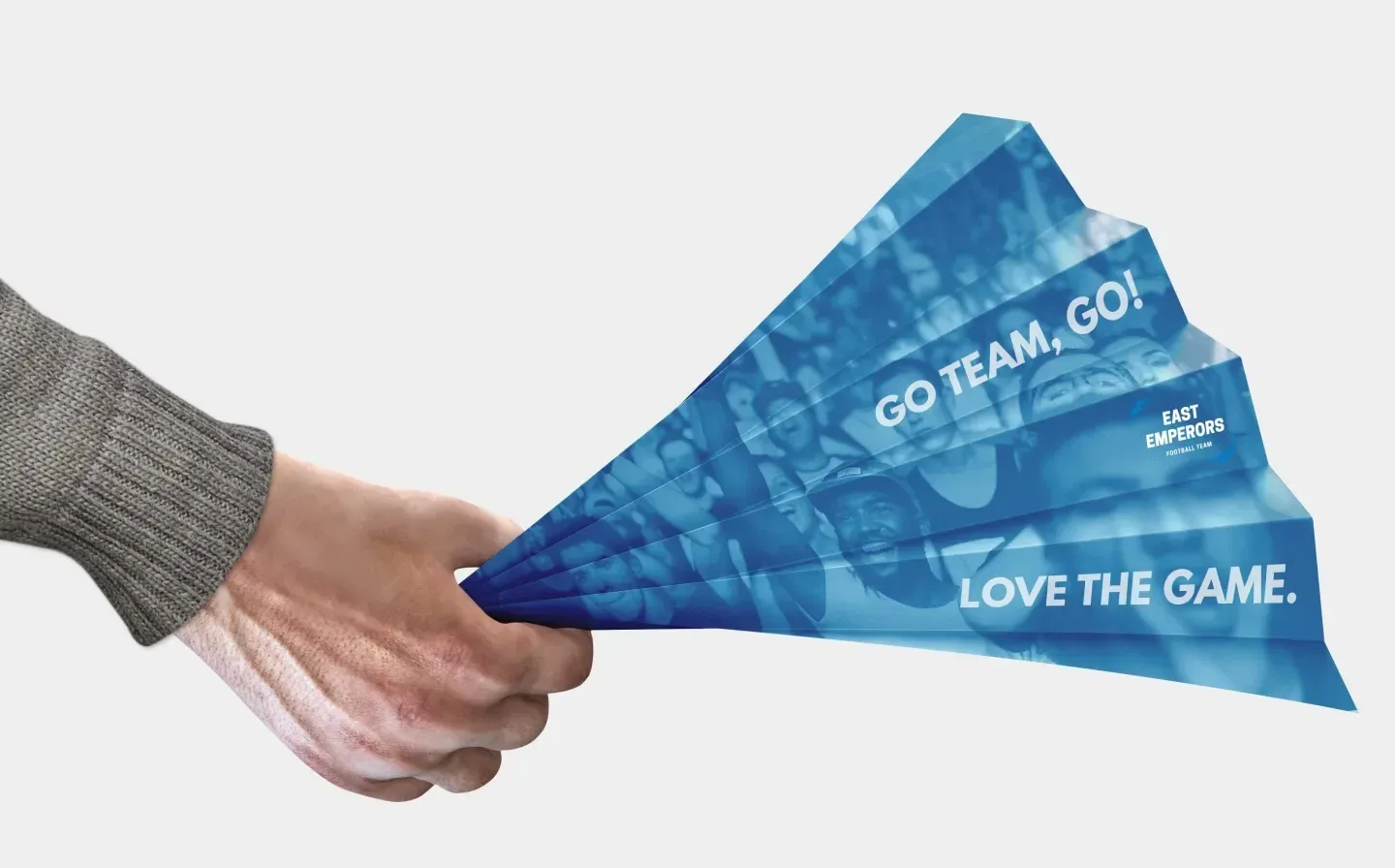 A person holds a paper fan clapper displaying the words "Go Team Go" in support of their team