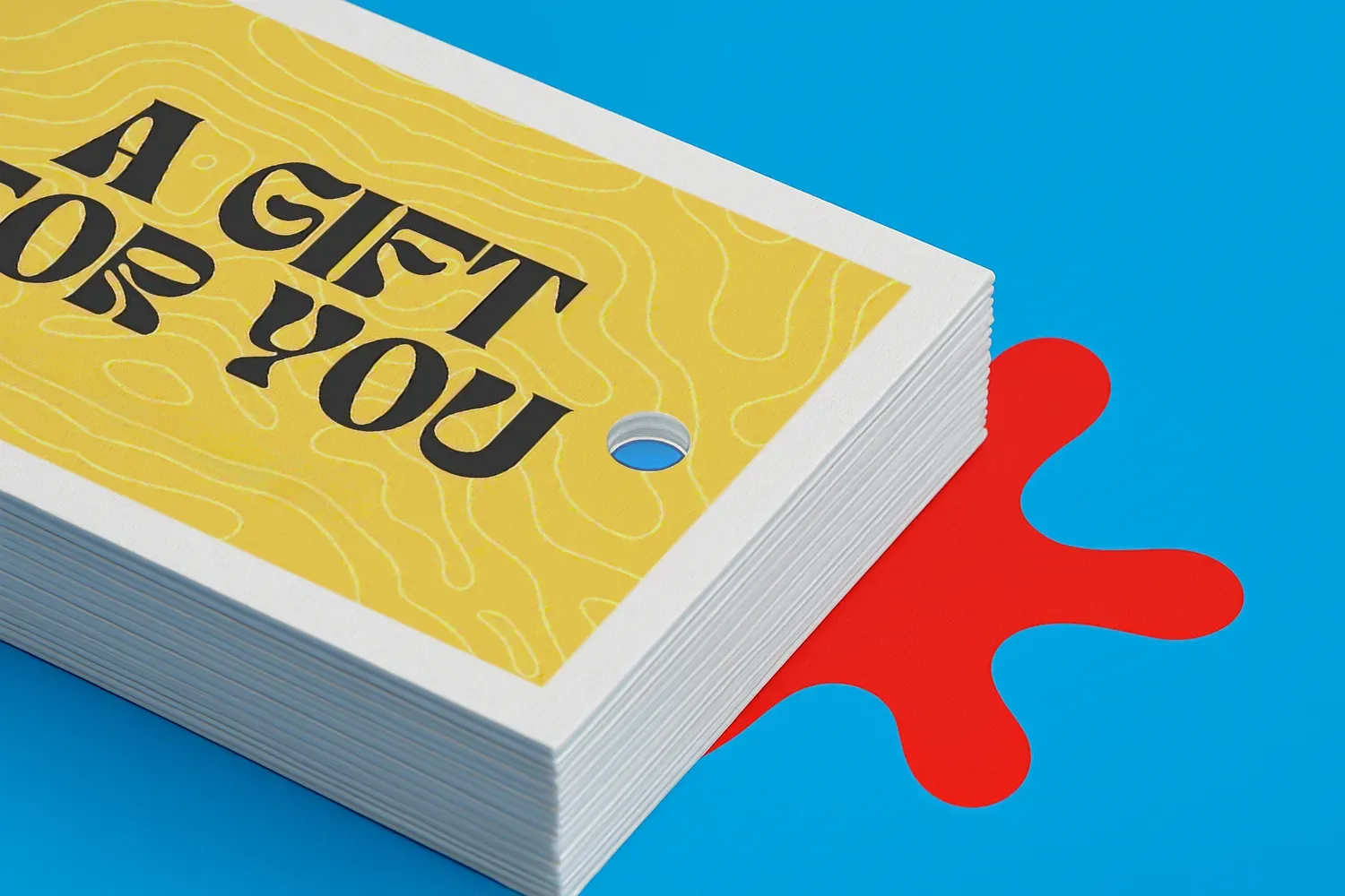 Stack of yellow "A Gift For You" cards on a blue surface with a red splash shape underneath.