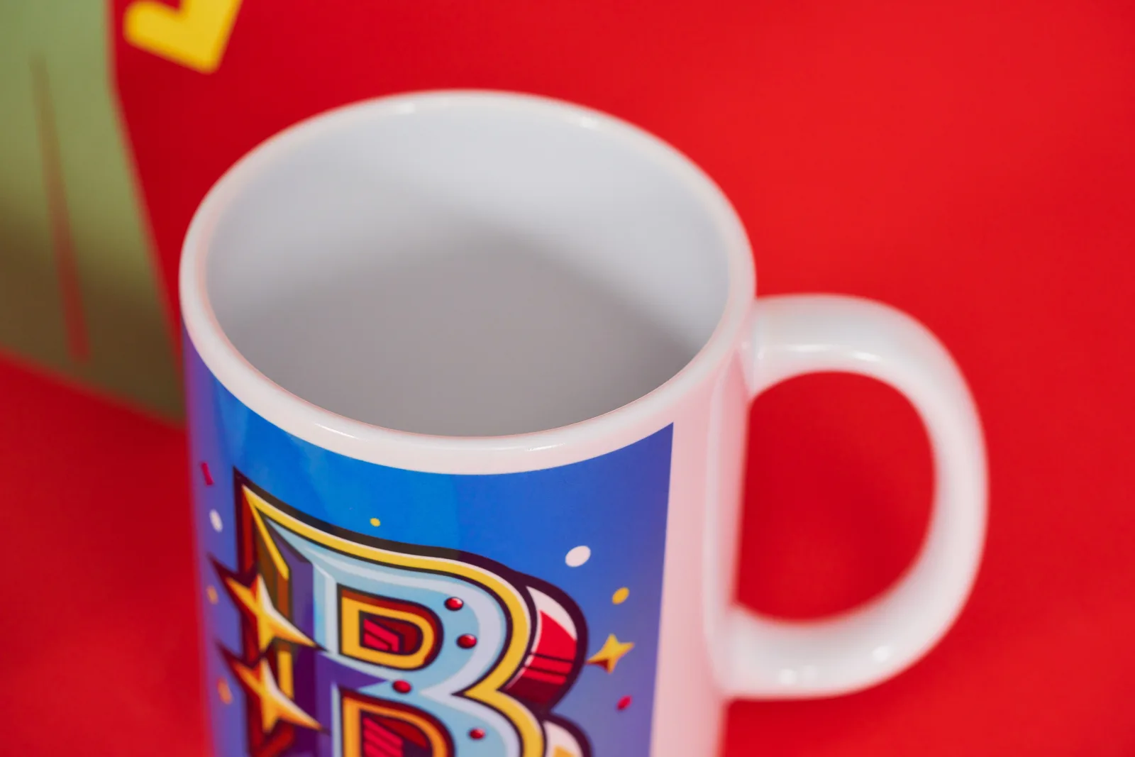 blue printed personalised mug with a decorative letter b on a bright red background