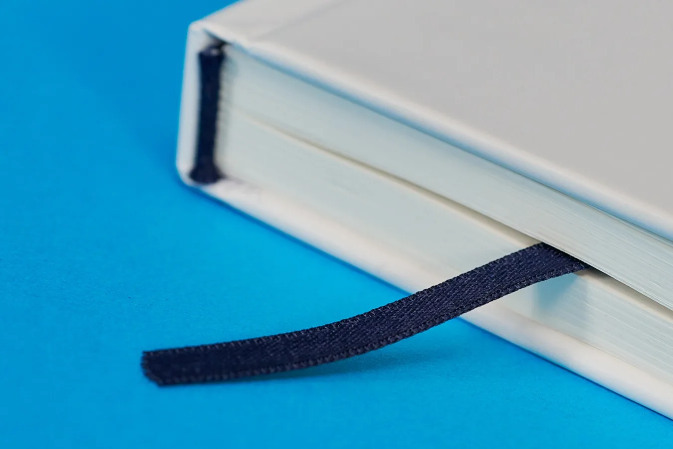 detail of a notebook showing black page marker ribbon on a bright blue background