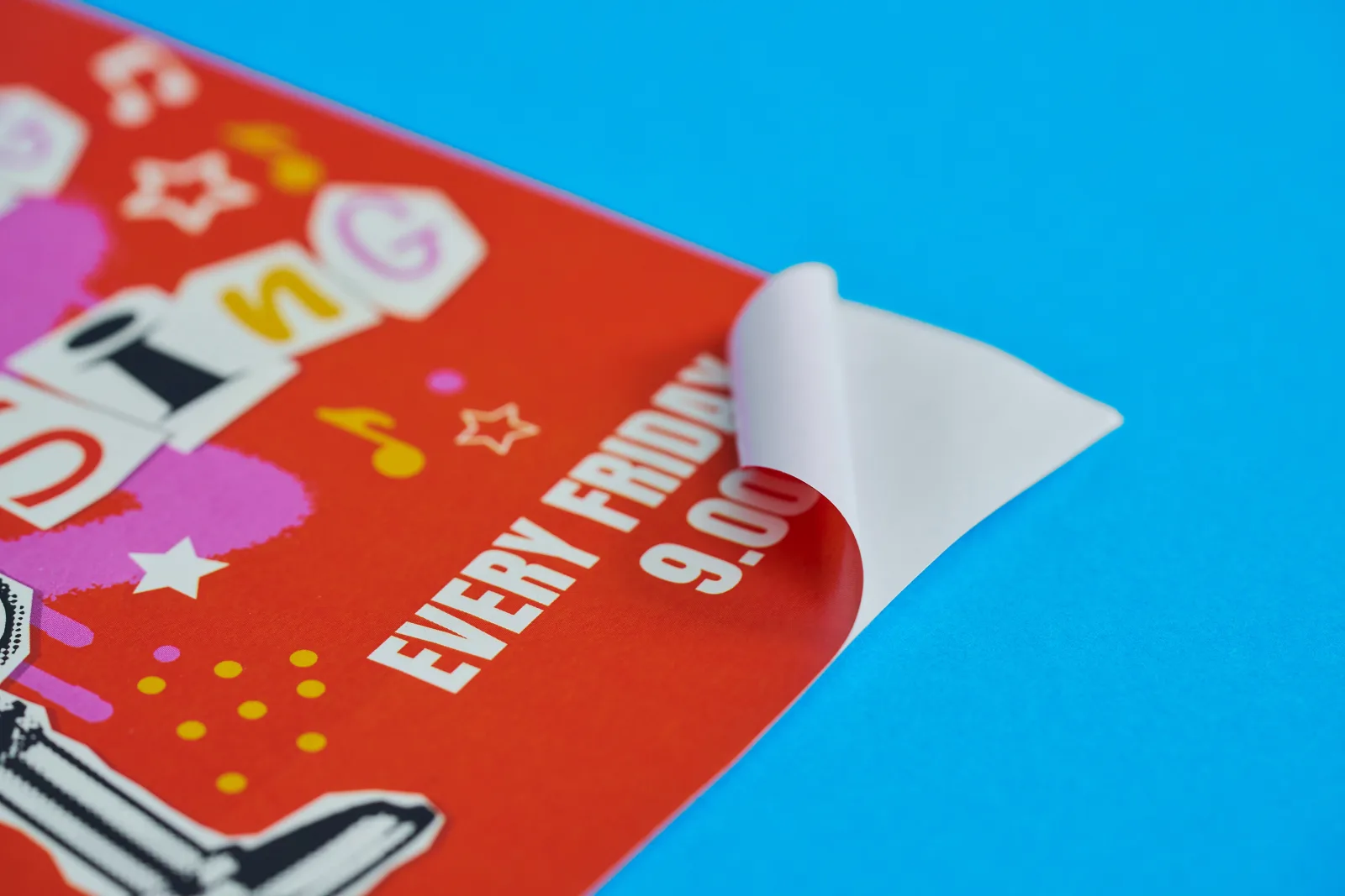 red sticker with text 'sing every friday 9.00' with corner peeled on a bright blue background