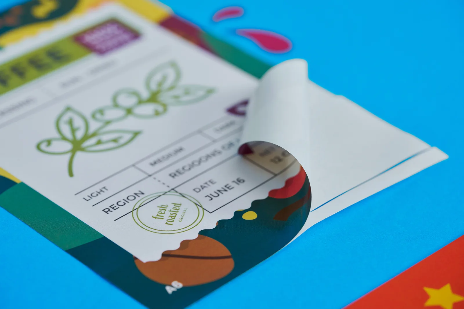 multi coloured coffee sticker with corner curled over on bright blue background