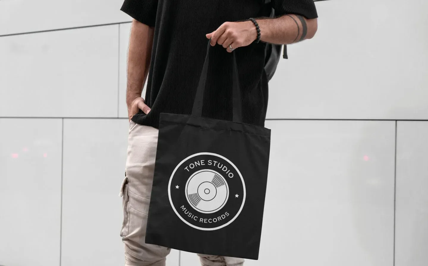 A man is seen with a black tote bag that prominently features a logo