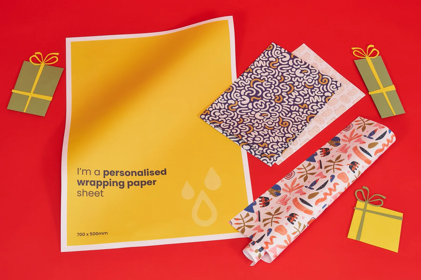 bright yellow sheet of wrapping paper with wording 'i'm a personalised wrapping paper sheet'. A sheet of blue folded wrapping paper and a rolled sheet of wrapping paper on a bright red backg
