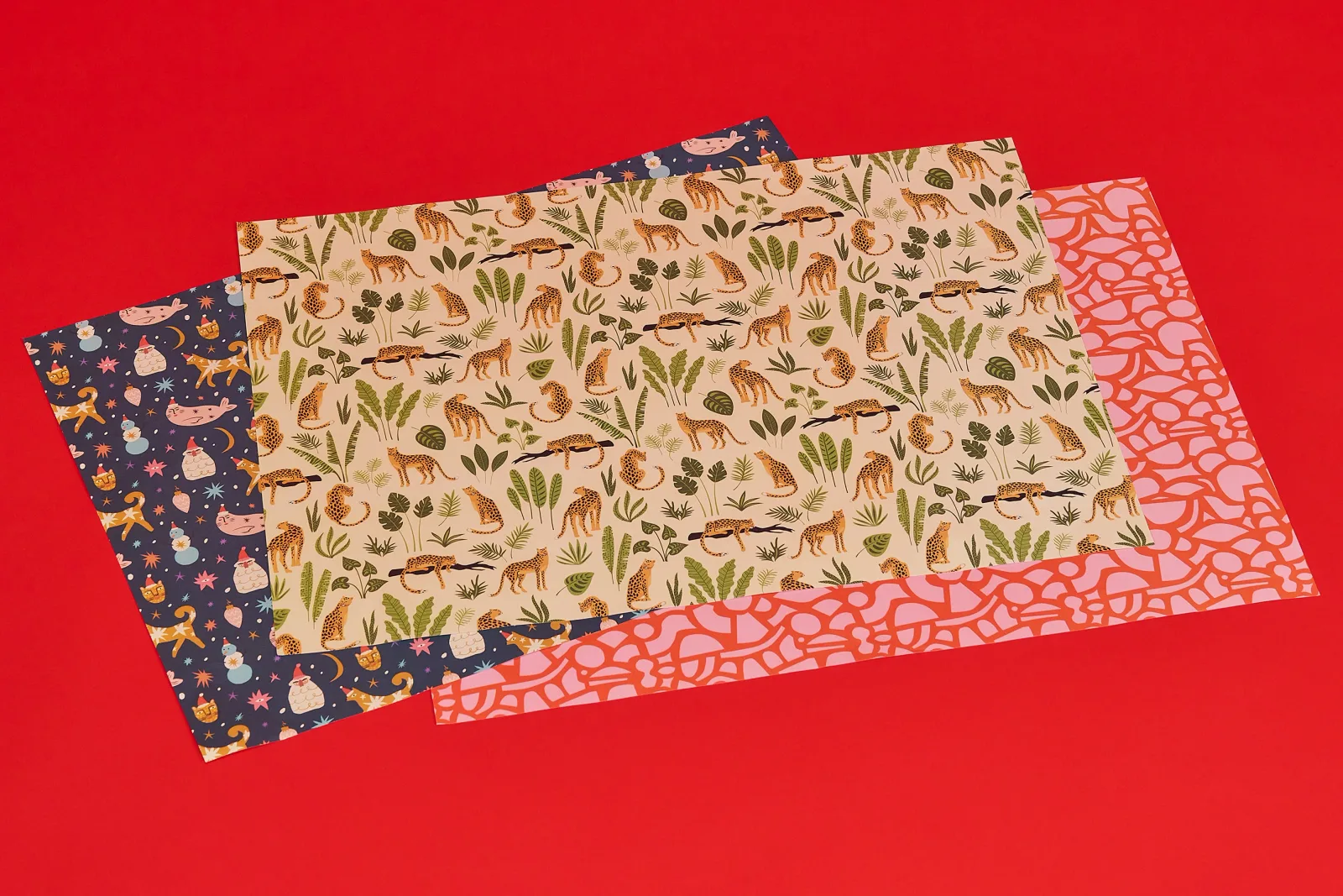 3 sheets of personalised wrapping paper with different prints on a bright red background