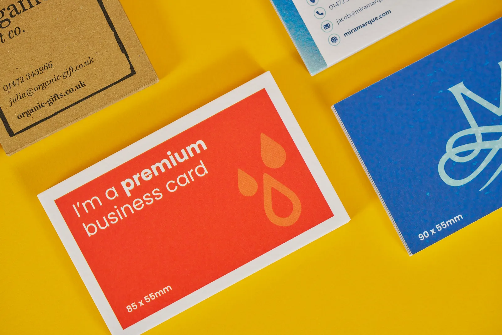 bright orange business card with copy 'i'm a premium business card' blue business card and kaft business card on a bright yellow background