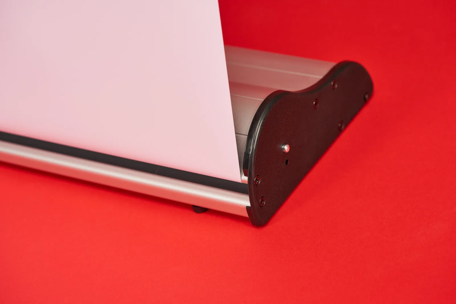 close up of a silver premium roller banner cassette with roller banner popping out on a bright red background