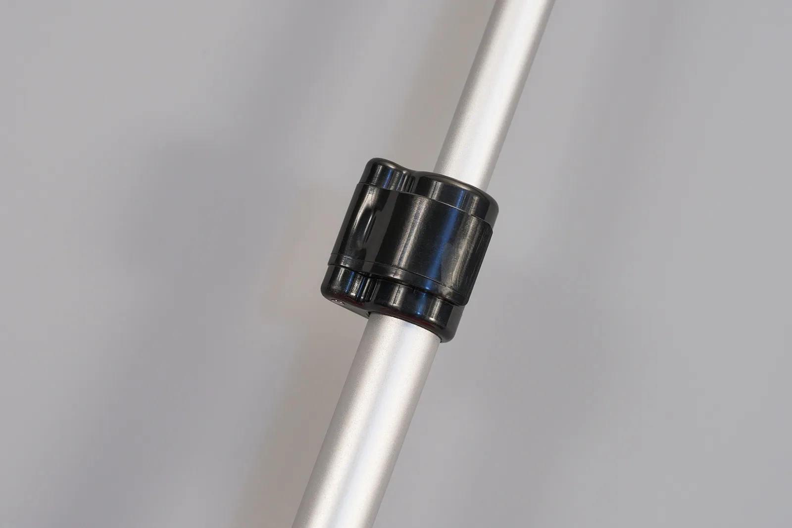 silver telescopic support pole with black plastic locking mechanism on a grey background