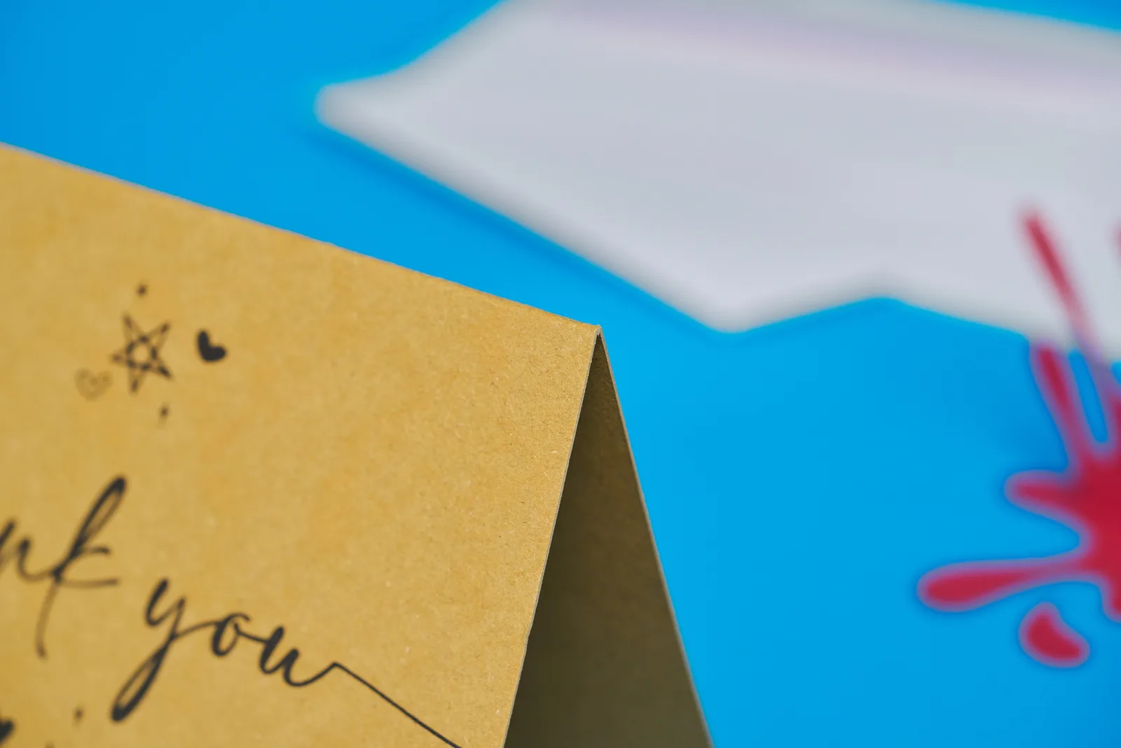 close up of a folded kraft paper printed greeting card with the text 'you' on a bright blue background