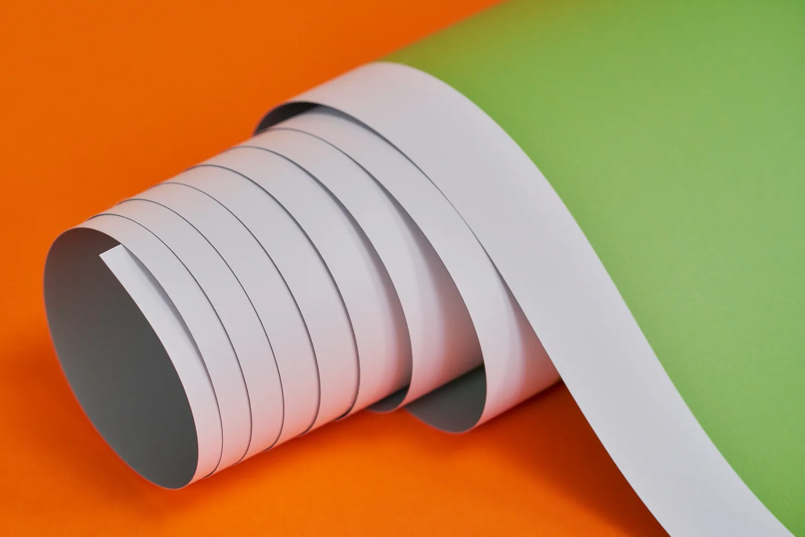 close up of a green printed rolled up replacement roller banner graphic on a bright orange background