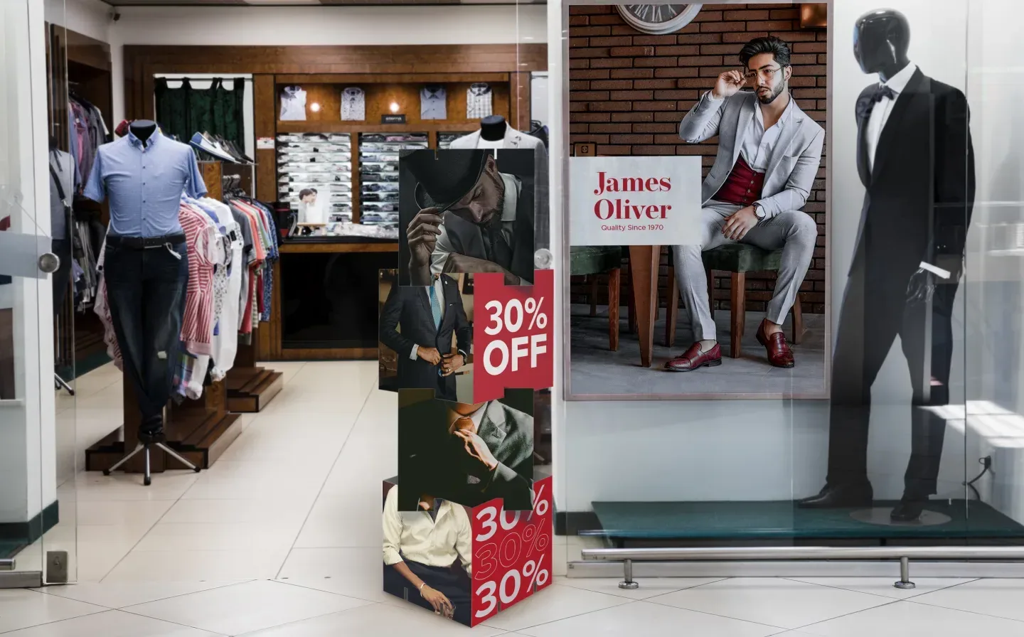 A stack of display cubes placed prominently at the entrance to a clothing store, surrounded by two mannequins in stylish clothing