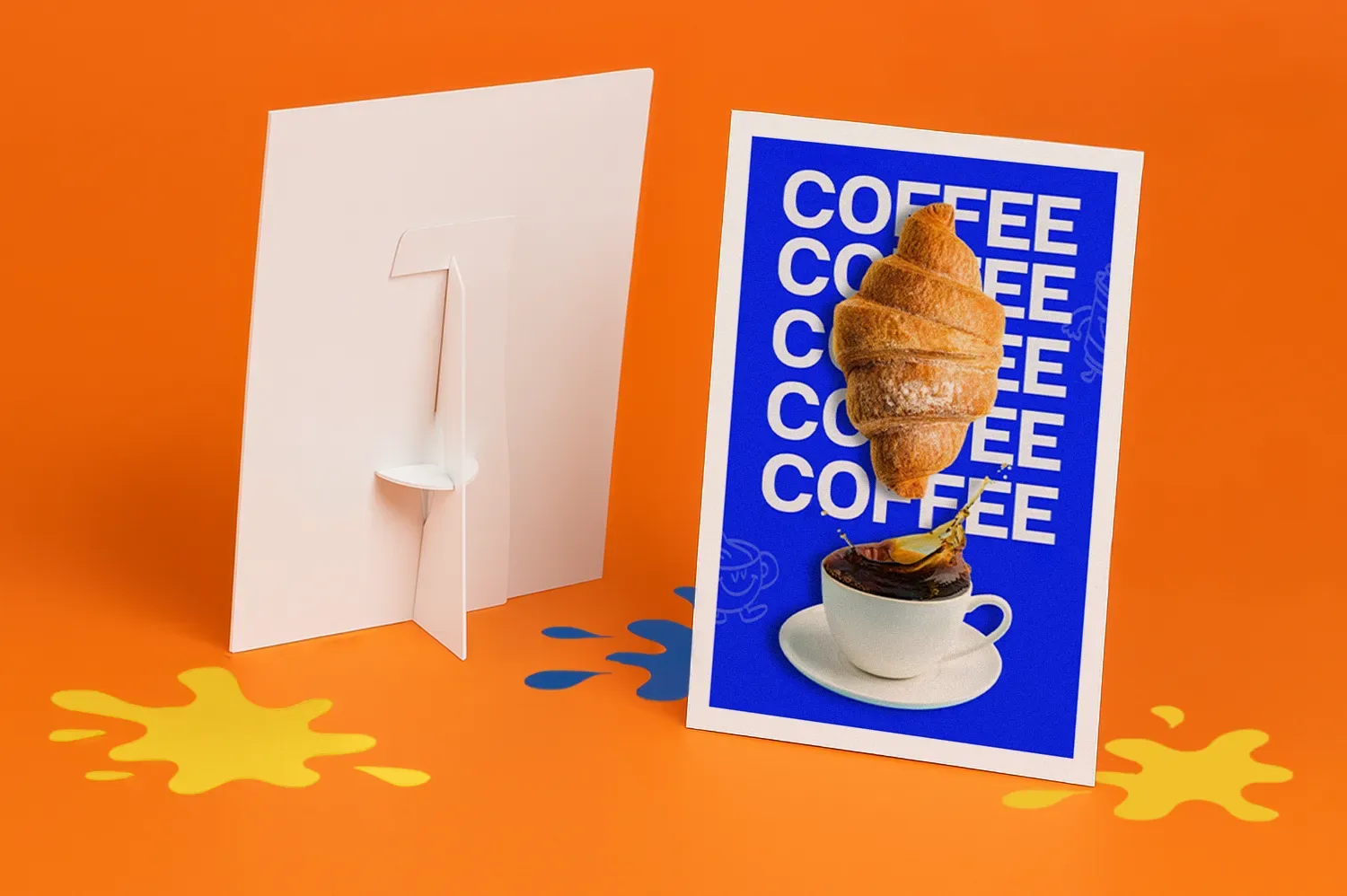 Strut card with croissant and coffee cup image, standing on orange surface with paint splatters.
