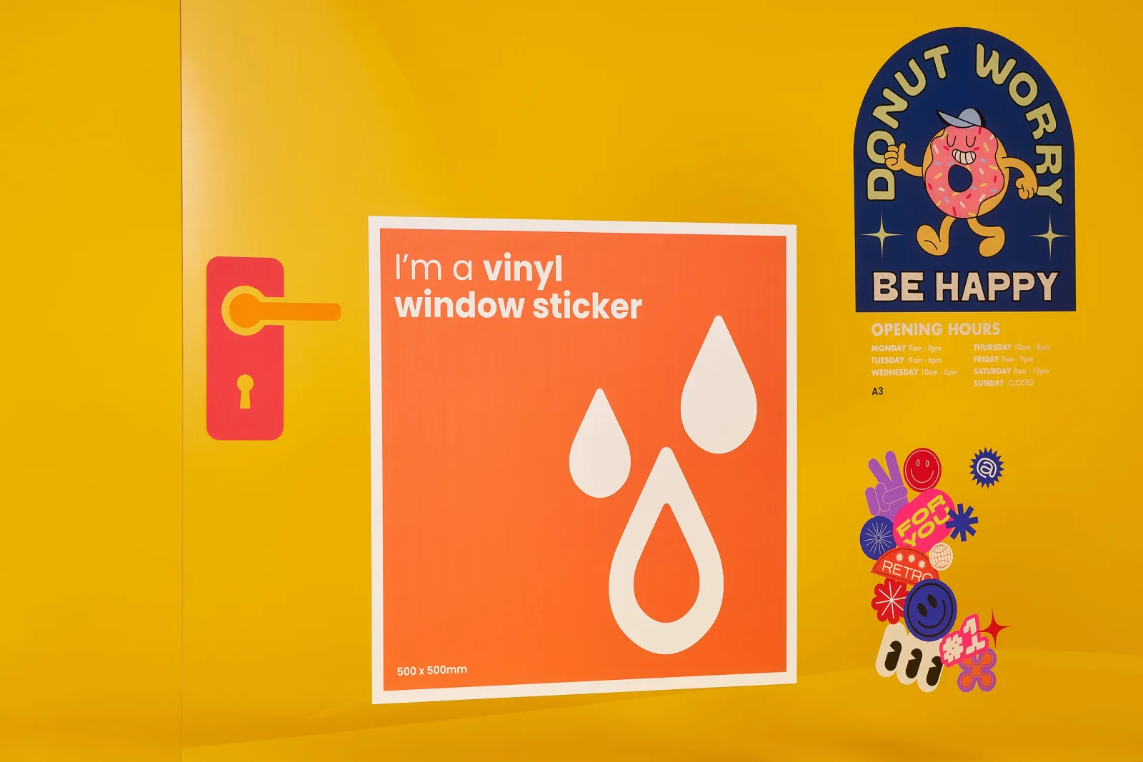 a glass door with lots of window stickers. a large orange square sticker with text 'i'm a vinyl window sticker 500 x 500mm' a cut to shape clear window sticker printed blue with text 'donut 
