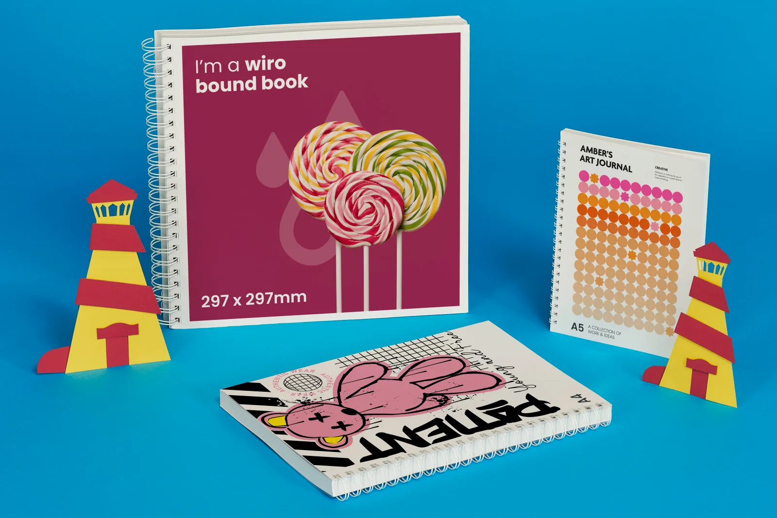 purple printed 297 x 297mm wiro bound book with multi colored lollipops. A4 printed wiro bound book with printed pink teddy bear. a5 printed wiro bound book with coloured dots on a bright bl